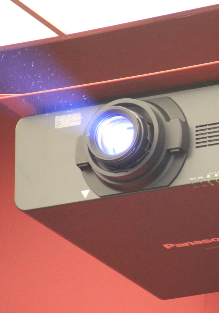 Beamer mit sichtbarem Projektions-Lichtstrahl als Beispiel für Audiovisions-Technik
